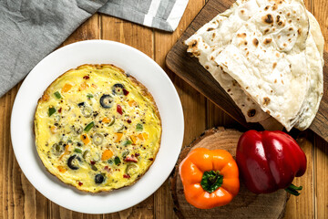 Colorful Vegetable Omelette with Pita Bread served in plate isolated on wooden table top view of arabic breakfast food