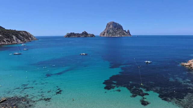 Cala Hort beach on Ibiza with a panoramic view of Es Vedra island Boats and catamarans anchored in the turquoise waters of the Mediterranean Sea