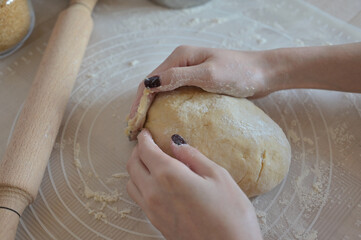 Baking ingredients for baking sweet buns, woman hands knead the dough on a silicone mat