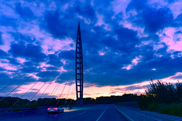 The sunset background creates a beautiful scenery with the suspension bridge and river