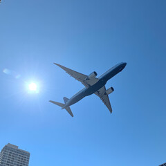 Obraz premium Airplane in Bright Blue Sky with Sunlight Glare