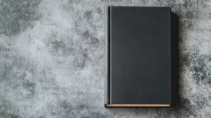 A sleek black menu book lies on a gray surface, softly lit by natural light