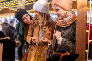 Diverse group of friends sharing joyful moment at christmas market, multicultural holiday celebration