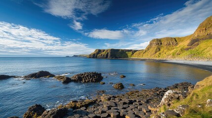 Fototapeta premium Scenic view of the Giant's Causeway, with its iconic stone pillars and rugged coastal scenery under a bright blue sky. No people included.