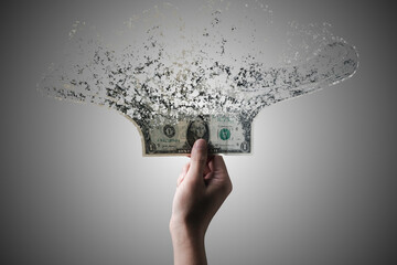 Hand holding US dollar banknote which it is disintegrate into dust particles for money hyper...