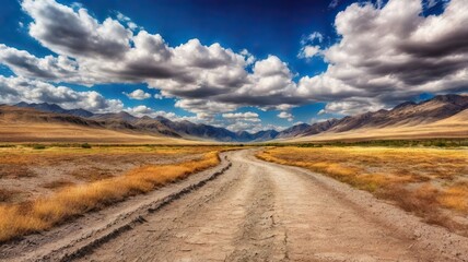 The Dusty Dirt Track Road. Highway in to the mountains, with blue skies and clouds. Ideal Desktop background or Wallpaper.