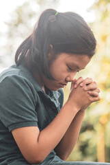 Fototapeta premium Pray concept.Asian child praying,hope for peace and free from disease,Hand in hand together by kid ,believes and faith in christian religion at church-vertical image.