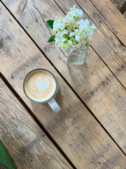 white flowers on wooden table with coffee heart latte art