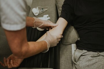 a nurse in gloves looks at the veins on the patient's arm to take blood for analysis