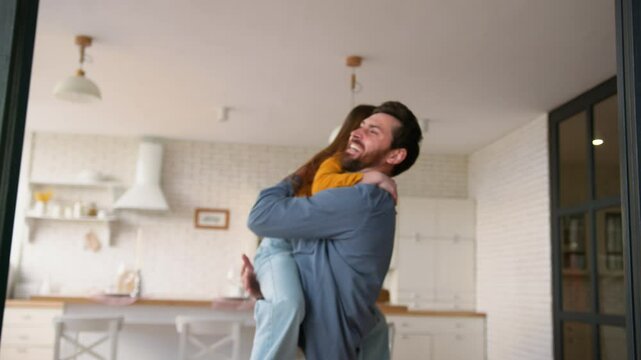 Joyful family Caucasian girl child running to happy father man guy male pick up little kid dad parent holding daughter smiling laugh spinning hugging cuddling embrace at home cheerful meeting weekend