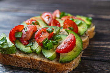 Avocado toast topped with tomato and green onion on a slice of carrot bread