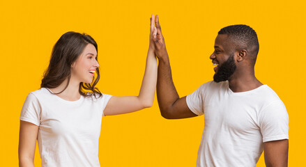 Success, Winning and Achievement Concept. Happy Interracial Couple Giving High Five To Each Other, Clapping Their Palms On Yellow Background, Panorama