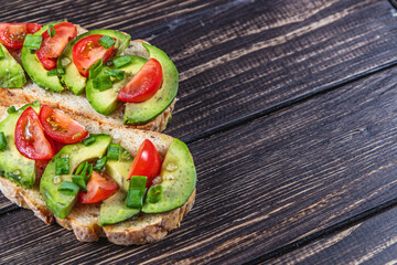 Avocado toast topped with tomato and green onion on a slice of carrot bread