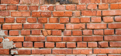 Fototapeta premium Panorama of red old brick wall. Detailed texture of aged masonry with broken bricks and peeling plaster. Urban, grunge, industrial, abstract backdrop. Pattern of loft interior or exterior background