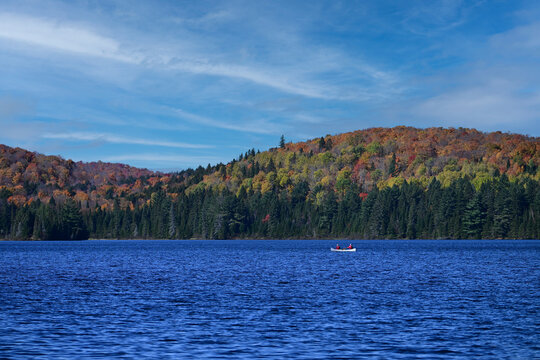 Fall scene of a remote lake with two people paddling a canoe 