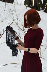 A red-haired girl examines a black lace handkerchief. Gothic winter atmosphere.