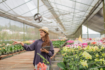 A woman joyfully interacts with colorful orchids in a lively, beautiful greenhouse