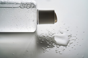 Bottle of facial toner or cleanser on white background with drops of product.
