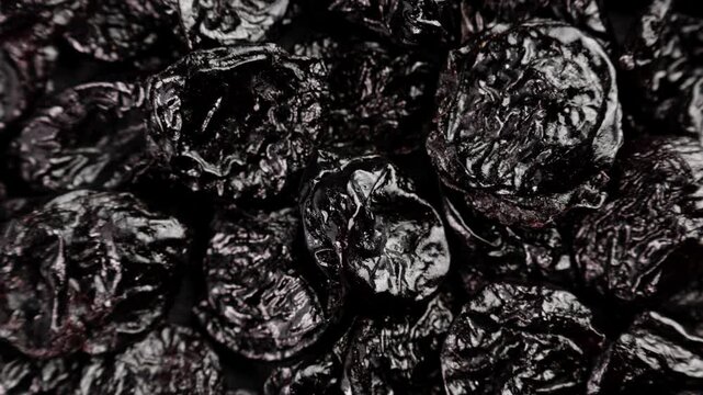 Rotating prunes. Healthy dried fruit. Snack. Pile of black fruits. Vegetarian nutrition. Prune. Top view. Close-up in 4K, UHD