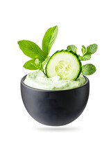Bowl of sauce tzatziki with a cucumber garnish, isolated on white background
