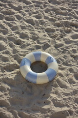 Blue and white inflatable swim ring on sandy beach. Perfect summer scene with beach vibes,...