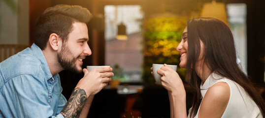 Young Lovers Enjoying Coffee Drinks Together During Romantic Date In Cafe. Love And Dating. Side View