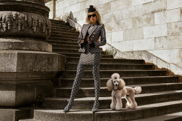 High fashion model. Glamour, stylish elegant woman in black and white suit, fashionable knee boots and classy hat is walking in the city. Female model in stylish look in the Paris.