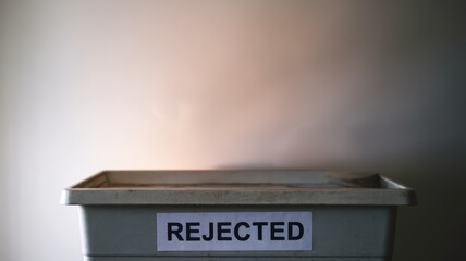 Trash bin labeled 'REJECTED' symbolizing waste and rejection in modern society.