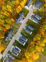 Semi-detached houses with solar panels in an autumn setting, drone view.