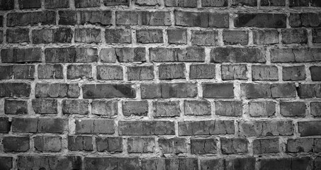 Fototapeta premium Black and white panorama of old brick wall. Texture of aged masonry with broken brick and peeling plaster. Urban, grunge, industrial, abstract backdrop. Pattern of loft interior or exterior background
