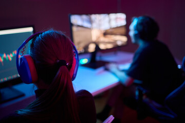 A devoted gamer sits in a vibrant neon lit room, completely engrossed in intense gameplay