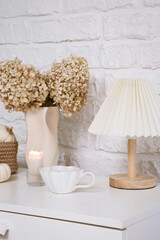 Autumn consept in interior.This arrangement features dried flowers, an elegant lamp, charming decor, pumpkins, cup of hot tea creating a cozy atmosphere.