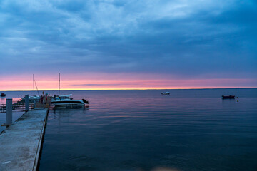 Obraz premium pier with yachts at sunset on calm sea