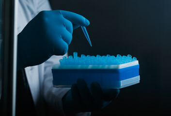 A scientist's hand in glove holds a pipette