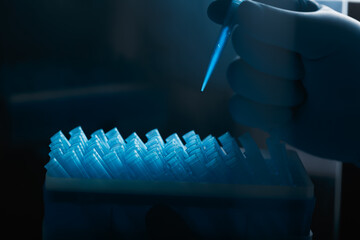 A scientist's hand in glove holds a pipette