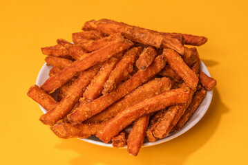 Homemade Orange Sweet Potato Fries with Salt and Pepper isolated on yellow background