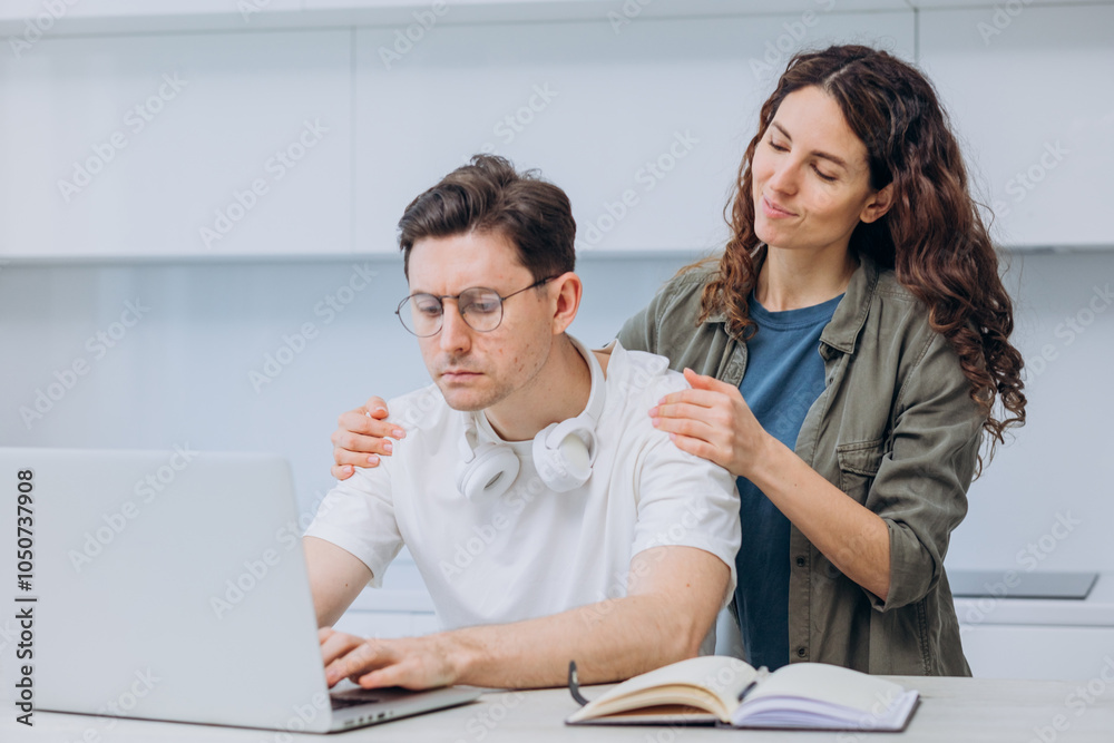 Wall mural woman playfully interrupts her partner working from home, immersed in business tasks at a desk in th