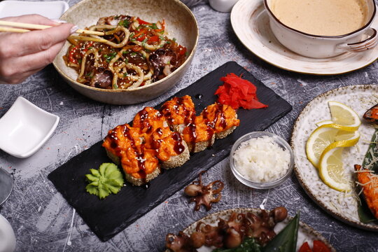 A table of Japanese cuisine consisting of sushi rolls noodles sea products
