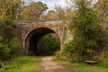 Fototapeta premium Hiking Trail Through A Railroad Arch Bridge In Autumn