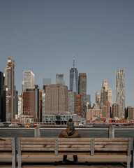 Naklejka premium Man sitting in a bench looking to New York 