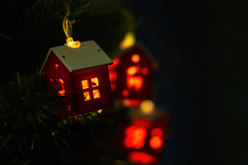 A Christmas garland in the form of houses, sparkling with lights on the tree, creates a cozy...