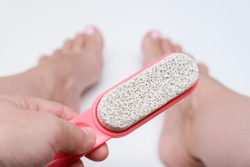 A person is holding a foot file and looking at their feet