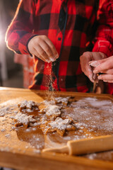 Cooking Christmas cookies with family. Father Mother and daughter hands top view on making gingerbread biscuits with cookie cutters, with New Year Christmas decoration