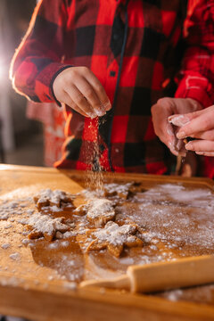 Cooking Christmas cookies with family. Father Mother and daughter hands top view on making gingerbread biscuits with cookie cutters, with New Year Christmas decoration