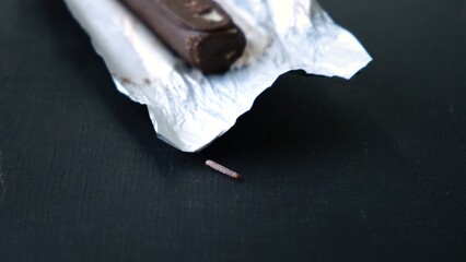Worms crawls on chocolate candy. Crawling larvae and eggs laid on food. Not fresh spoiled product....
