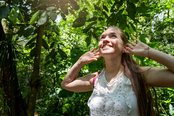 Mujer escuchando atentamente los sonidos de la naturaleza, estando en un bosque tropical lleno de...