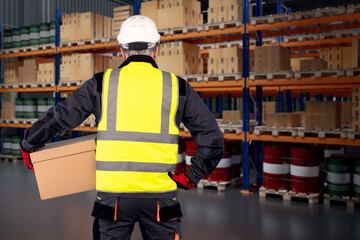 Man with box stands in warehouse. Storage company worker with his back to camera. Man with box...