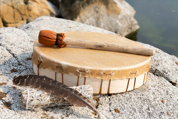 An image of a handmade leather meditation drum with white sage smudge stick and sacred feather.