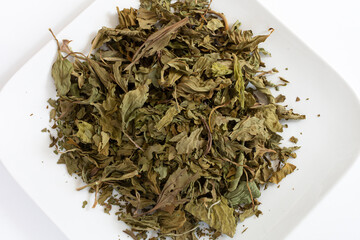 A top view image of dried broadleaf plantain leaves on a white ceramic plate. © Pam Walker