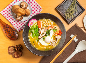 Curry Udon with beetroot,shrimp,noodles, mushroom,chopsticks and spoon served in bowl isolated on wooden table top view of taiwan food